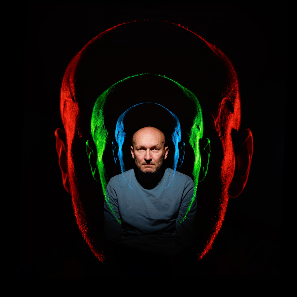 Photo by Samuel Galanský: Abstract portrait with multiple heads nested inside each other, outlined with red, green, and blue neon light.